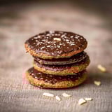 Three stacked chocolate cookies with nuts on top.