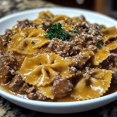 Une assiette de pâtes papillon avec des viandes hachées dessus.