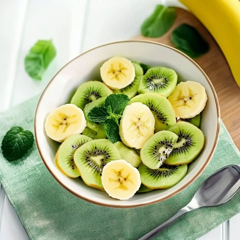 A bowl of fruit salad with kiwi and bananas.