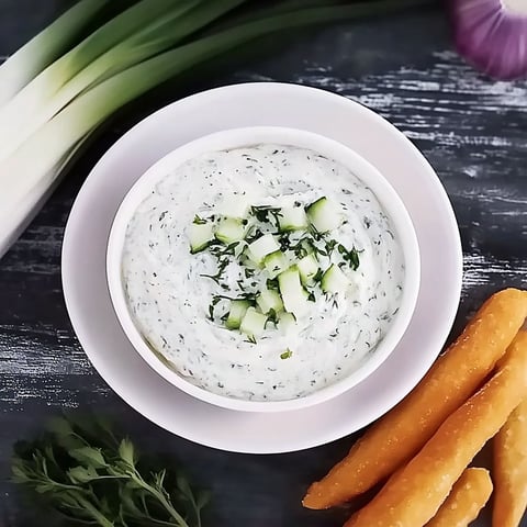 A white bowl filled with dip and vegetables.