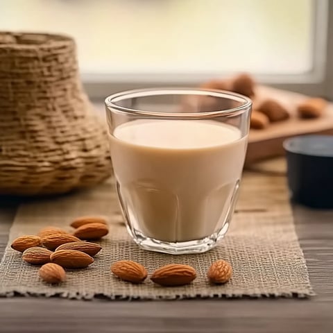 A glass of milk with almonds on a table.